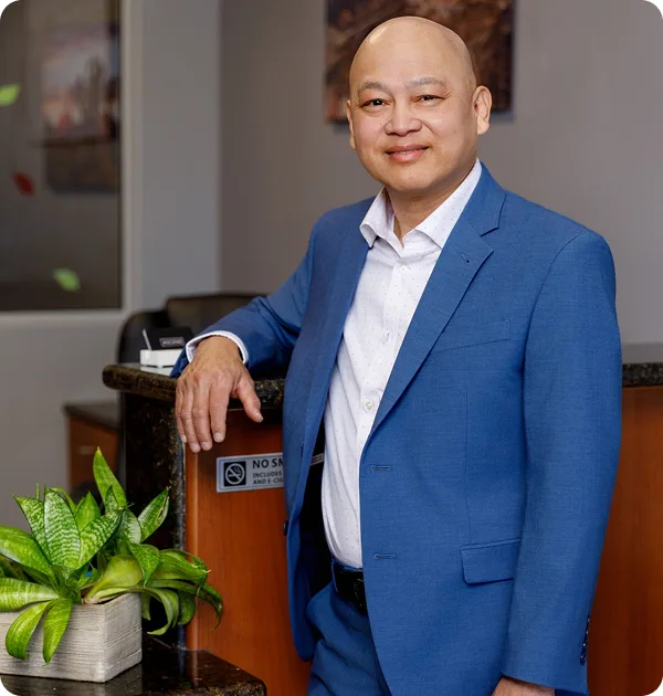 Dr. Timothy Luong in a blue suit smiling confidently as a dentist in Henderson NV
