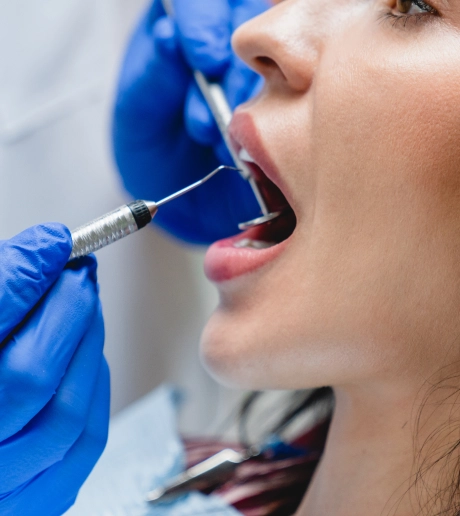 A dental professional in blue gloves using a syringe during a preventive care procedure at Ascend Dental Studio in Henderson NV