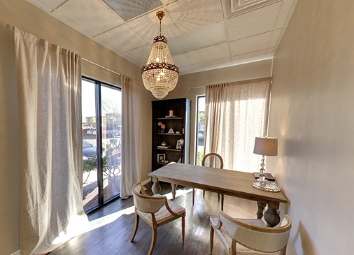 An elegantly designed consultation room at Ascend Dental Studio in Henderson NV with a crystal chandelier wooden table and neutral decor