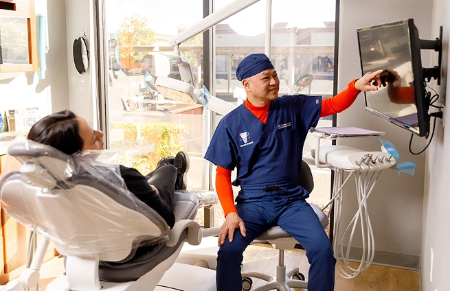 Dr. Timothy Luong in scrubs pointing to dental equipment at Ascend Dental Studio in Henderson NV