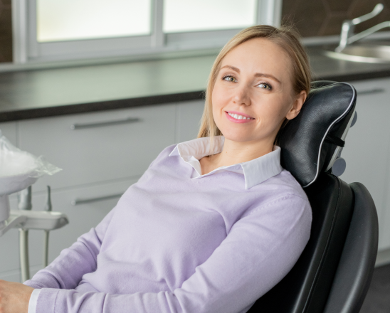 Smiling female patient relaxed in dental chair wearing lavender scrubs in Henderson dental office.