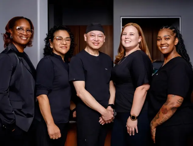 Professional dental team of five smiling members in black uniforms at Henderson, Nevada practice.